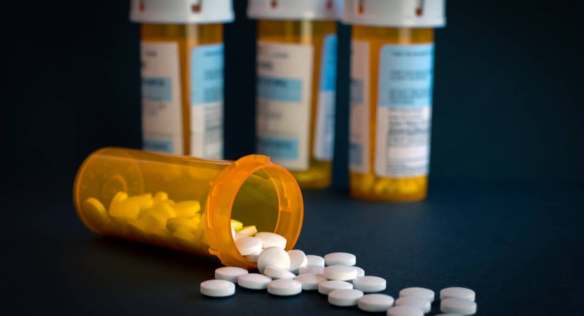 Bottle of Perscription Pills Tipped Over And Falling Out Of Container In Fornt Of Other Pill Bottles To Represent The Michigan Opioid Settlement