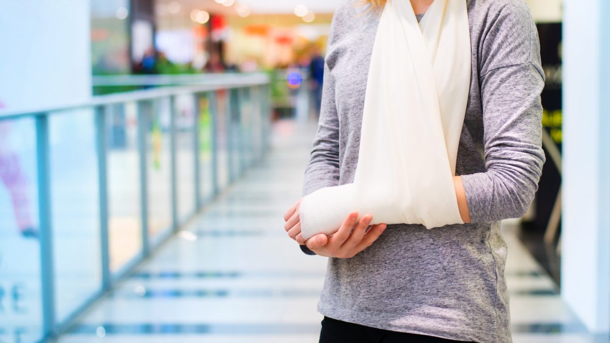 Lady with injured arm stands in shopping mall