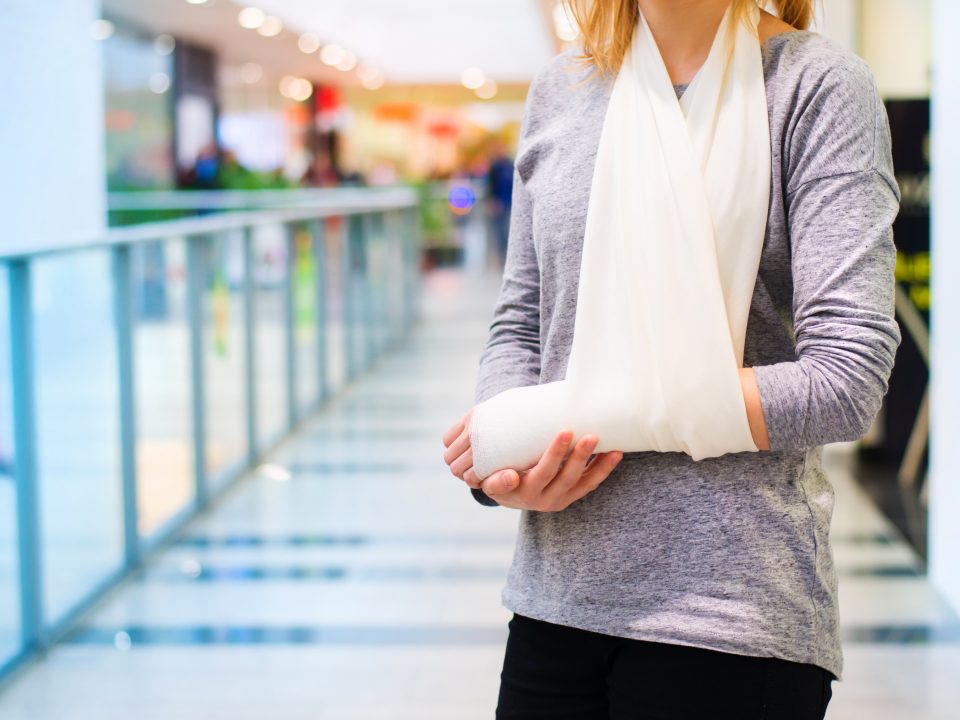 Lady with injured arm stands in shopping mall