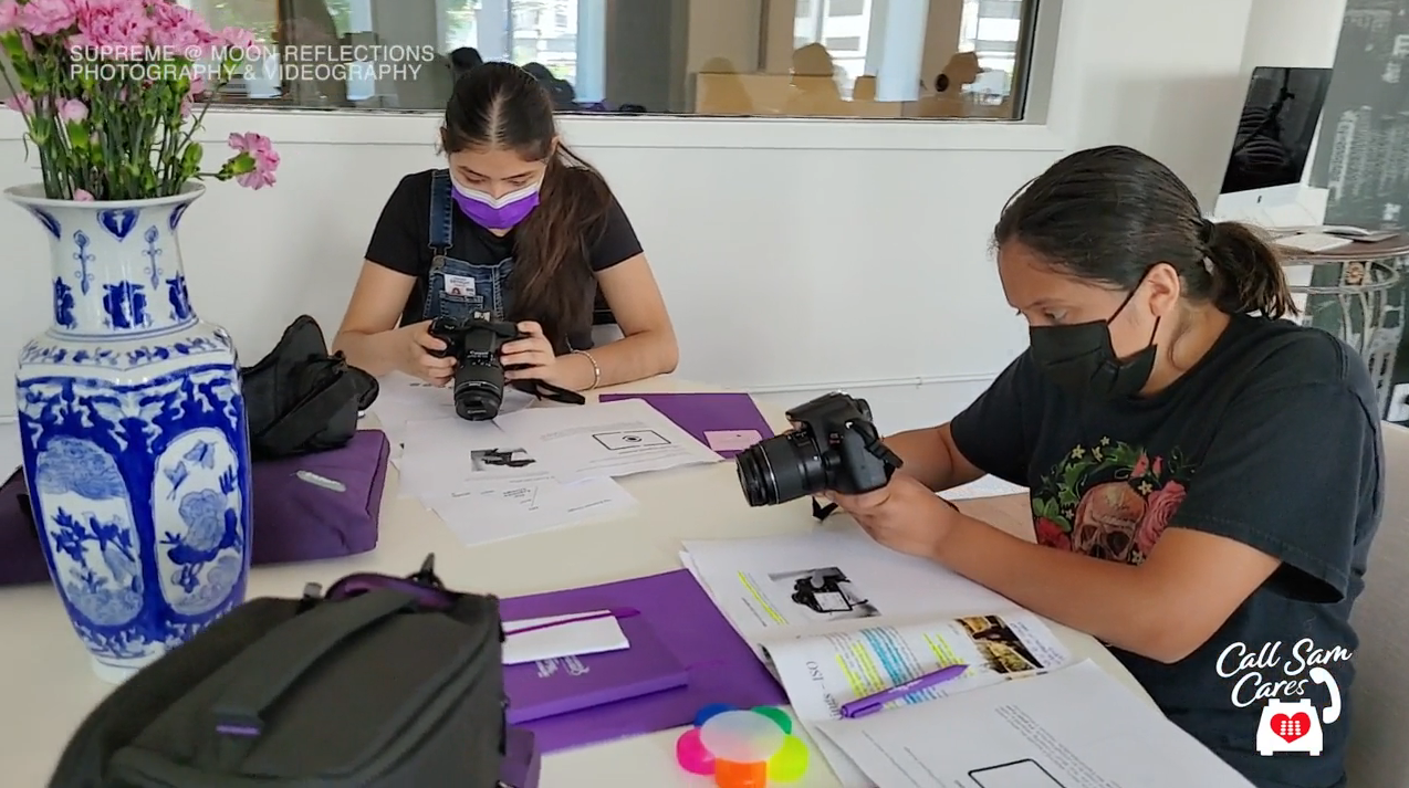 students around a table working with cameras