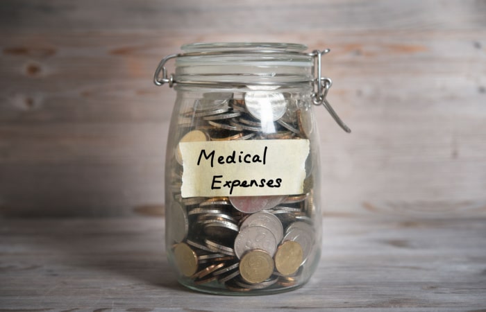 Jar full of coins with the words medical expenses written on the front of the jar