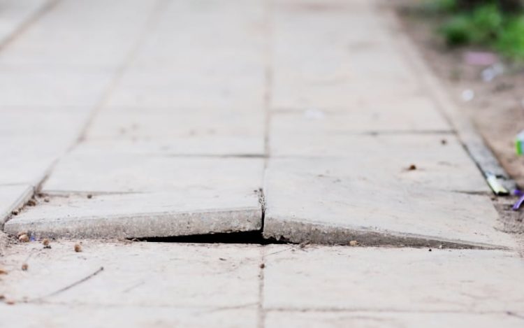 a public sidewalk with a heaving crack causing danger