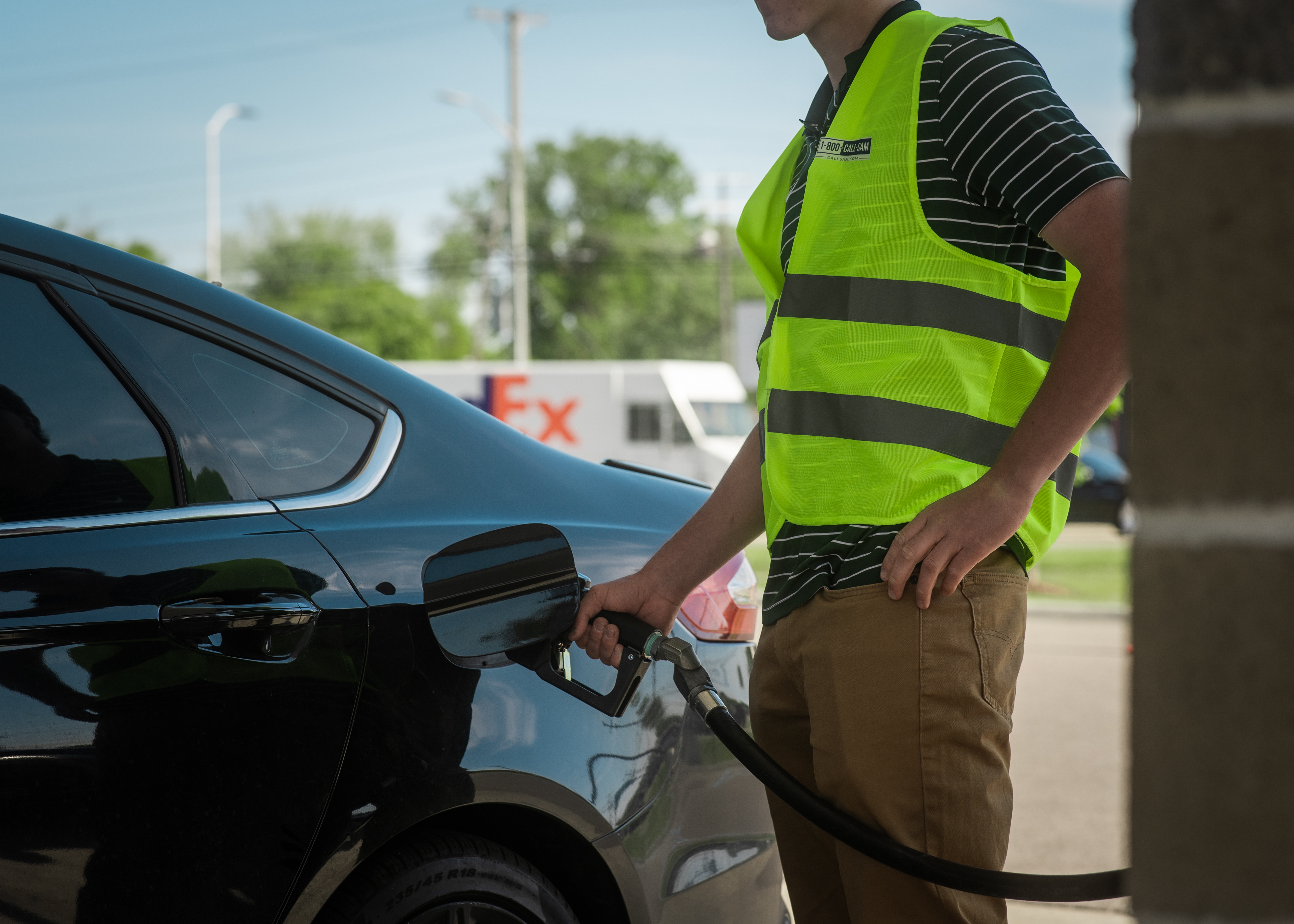 Volunteer pumping gas wearing a safety vest for the Gas Giveaway program