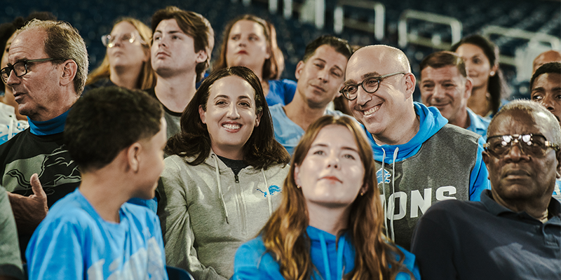 People sitting in the stands of a Stadium at a football game