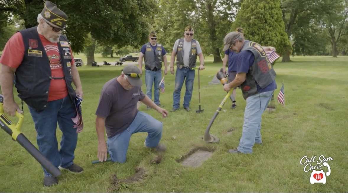 People bent down cleaning grave stones in a grave yard
