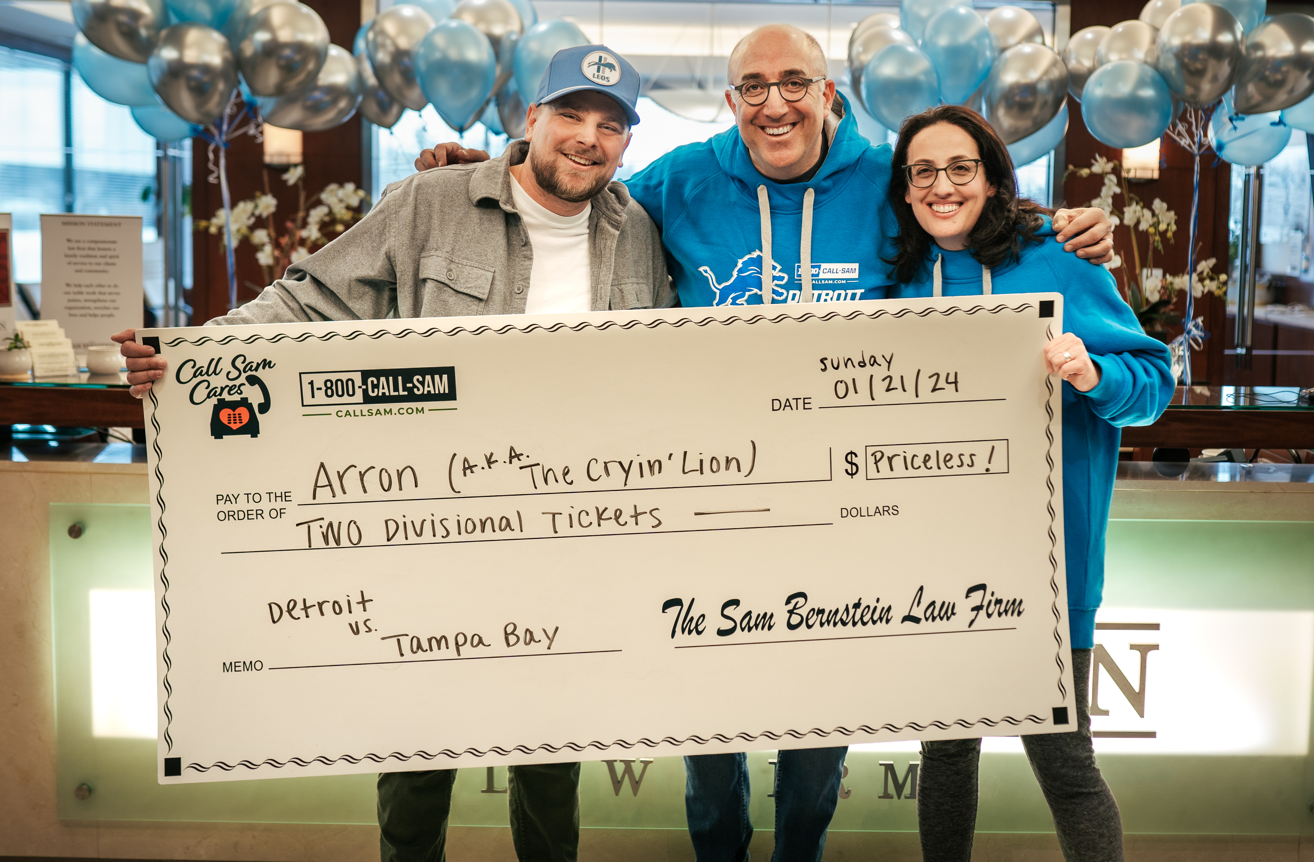 three people standing behind a giant check for a donation being made