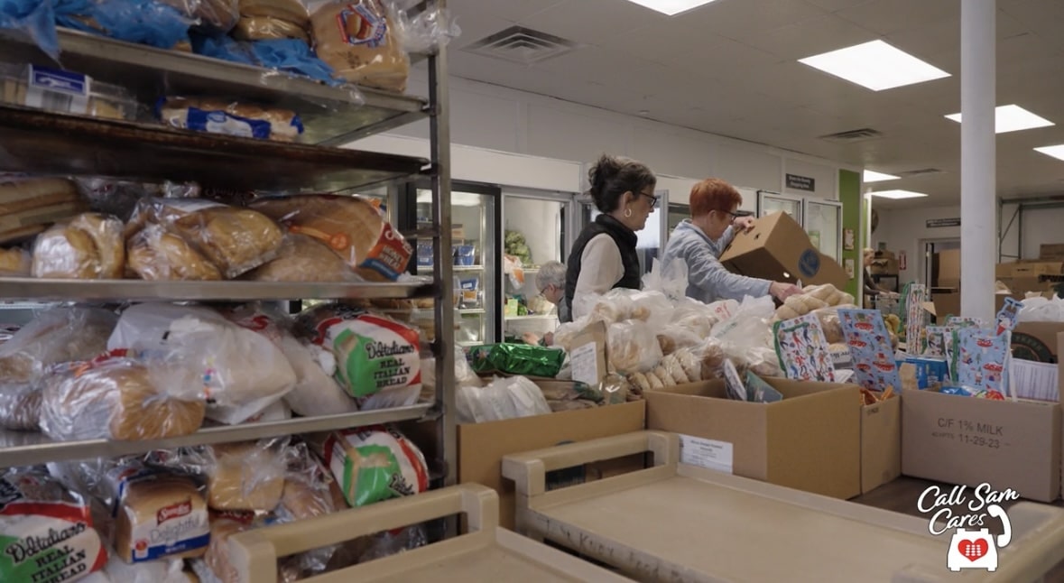 stock pike of food on racks with two volunteers working in the background.