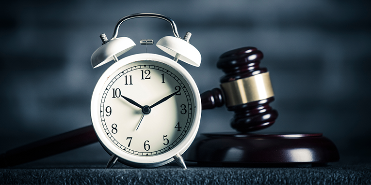 a clock in front of a judges gavel on a desk