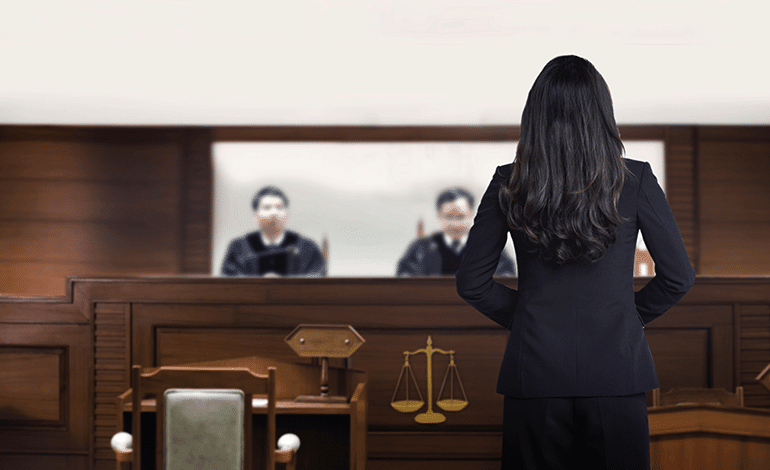 Female Attorney standing before two male judges in a court room