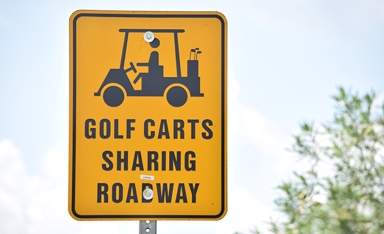 Sign with Golf Cart On It THat Says Golf Carts Sharing Road