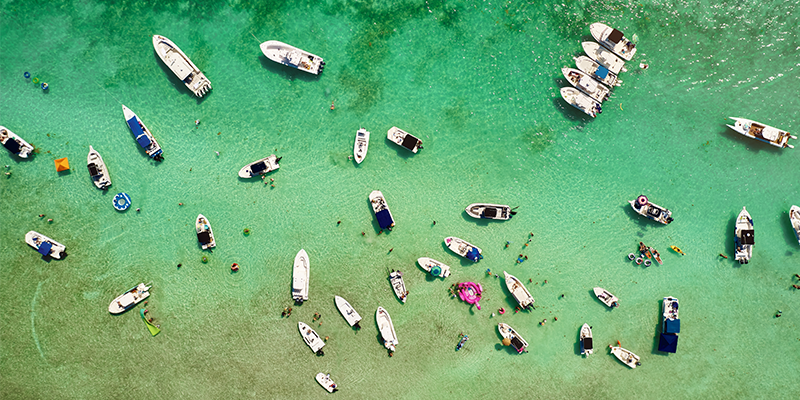 aerial view of several boats and people enjoying activities at a large sandbar in the water.