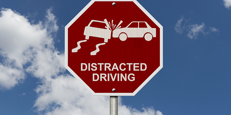 Picture of red stop-sign that has the words distracted driving and a icon style car crash