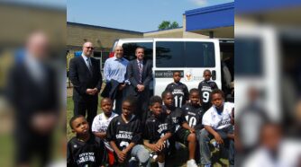 Mark Bernstein and team standing with kids in sports uniforms in front of van