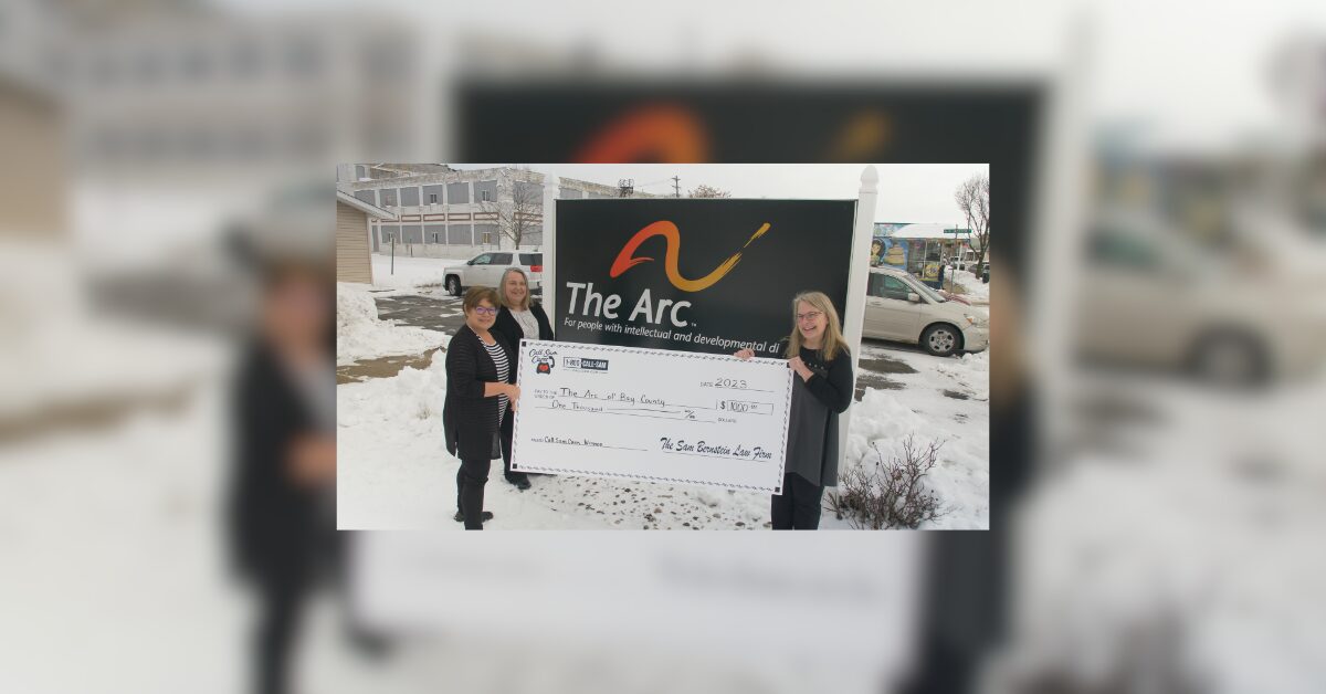 2 women holding large format check outside in snow