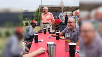 Group of people talking and laughing at picnic table with Mark and Sam Bernstein