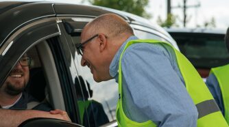 Mark Bernstein shaking a mans hand who is inside a car